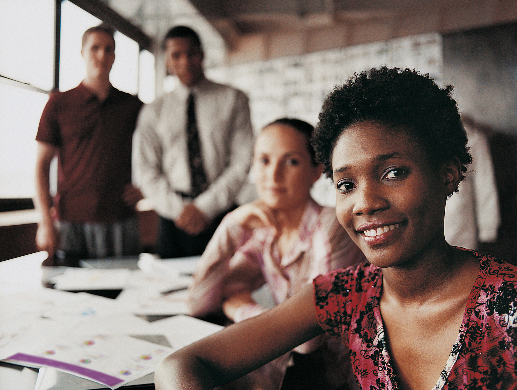 Portrait of a Fashion Designer Sitting in Front of Three of Her Colleagues at a Desk