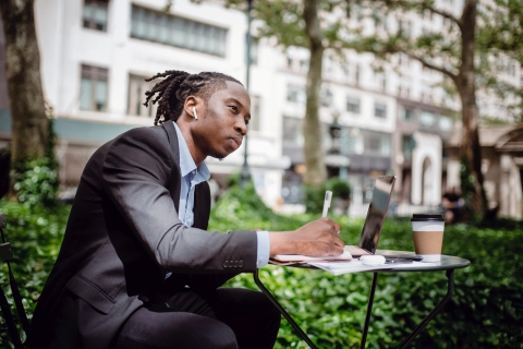 Man taking notes at desk outside