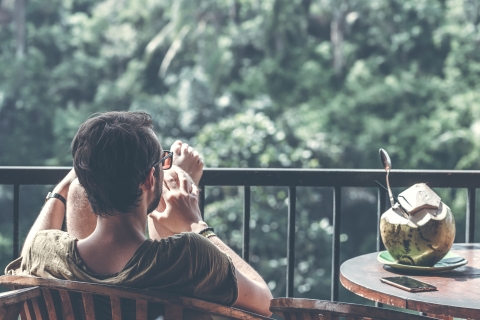 Man sitting outside with a coconut beside him