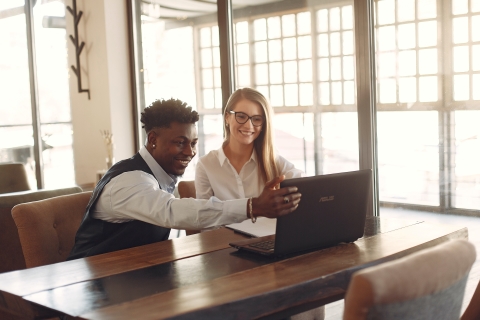 Team of two people smiling at a laptop screen